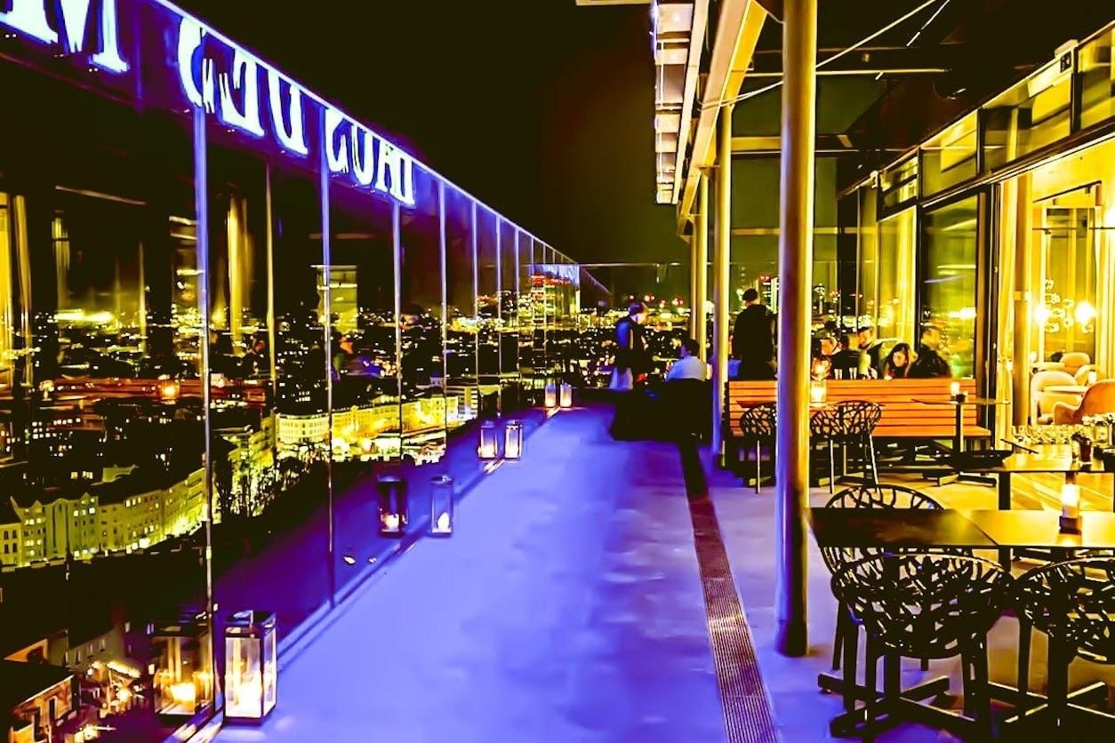 Foto: Rooftop Terrasse am Abend mit vielen Stühlen und Tischen
