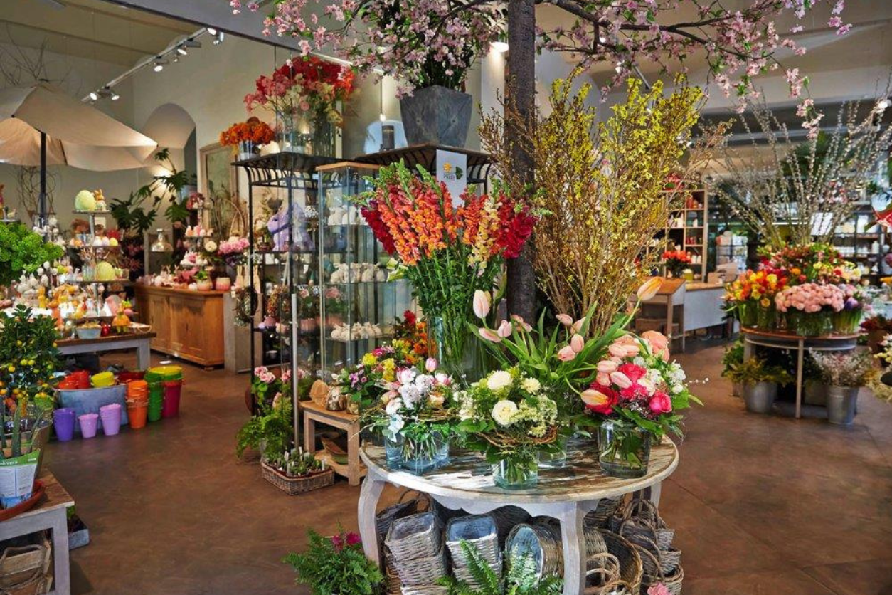 Foto: Blumengeschäft mit Glasvitrinen Tischchen und vielen unterschiedlichen Blumengestecken