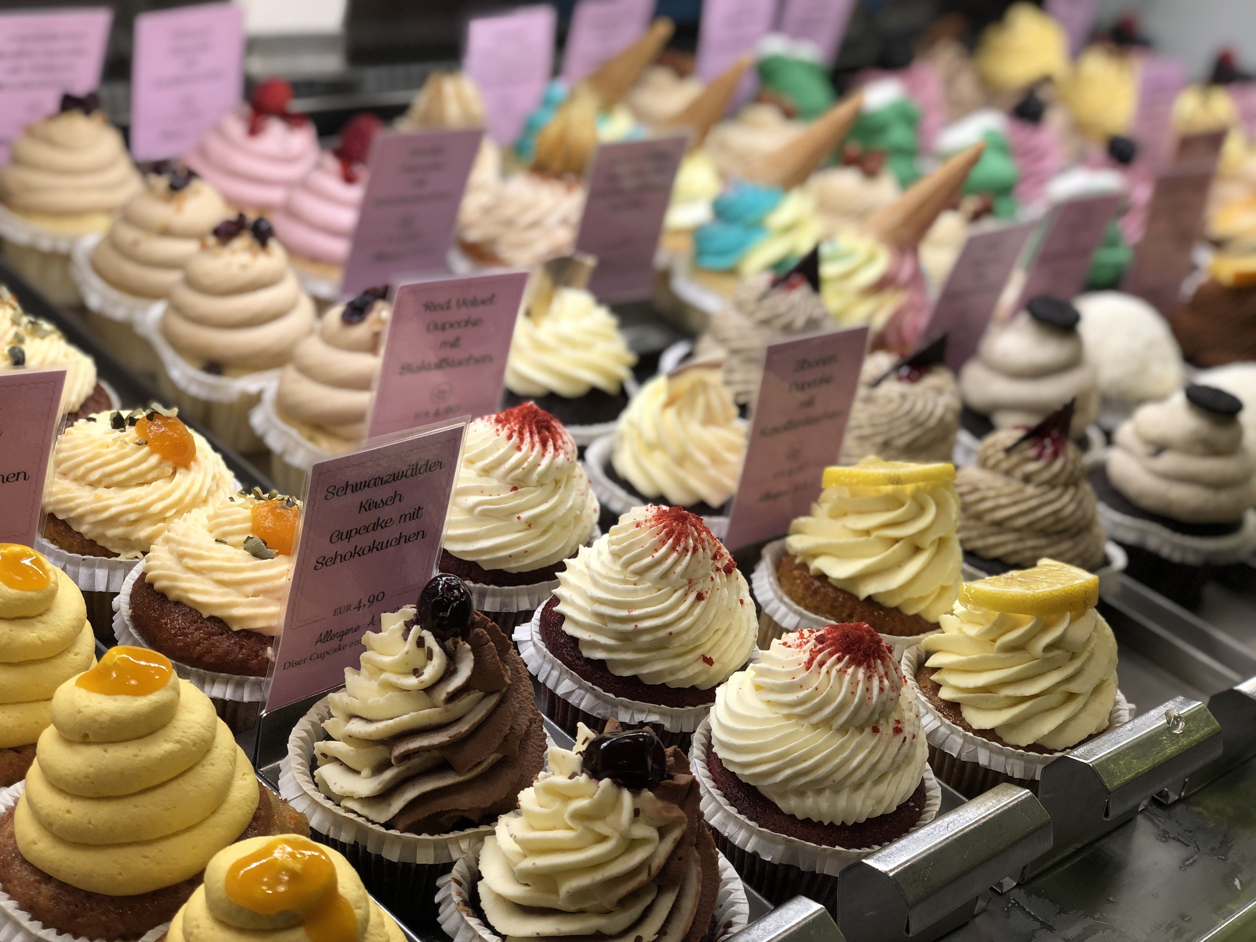 Foto: Mehrere Cupcakes verschiedener Sorten in einer Vitrine aufgestellt
