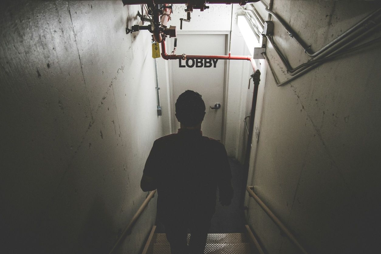 Foto: Eine Person geht in einen Keller und vor ihm ist eine verschlossene Tür