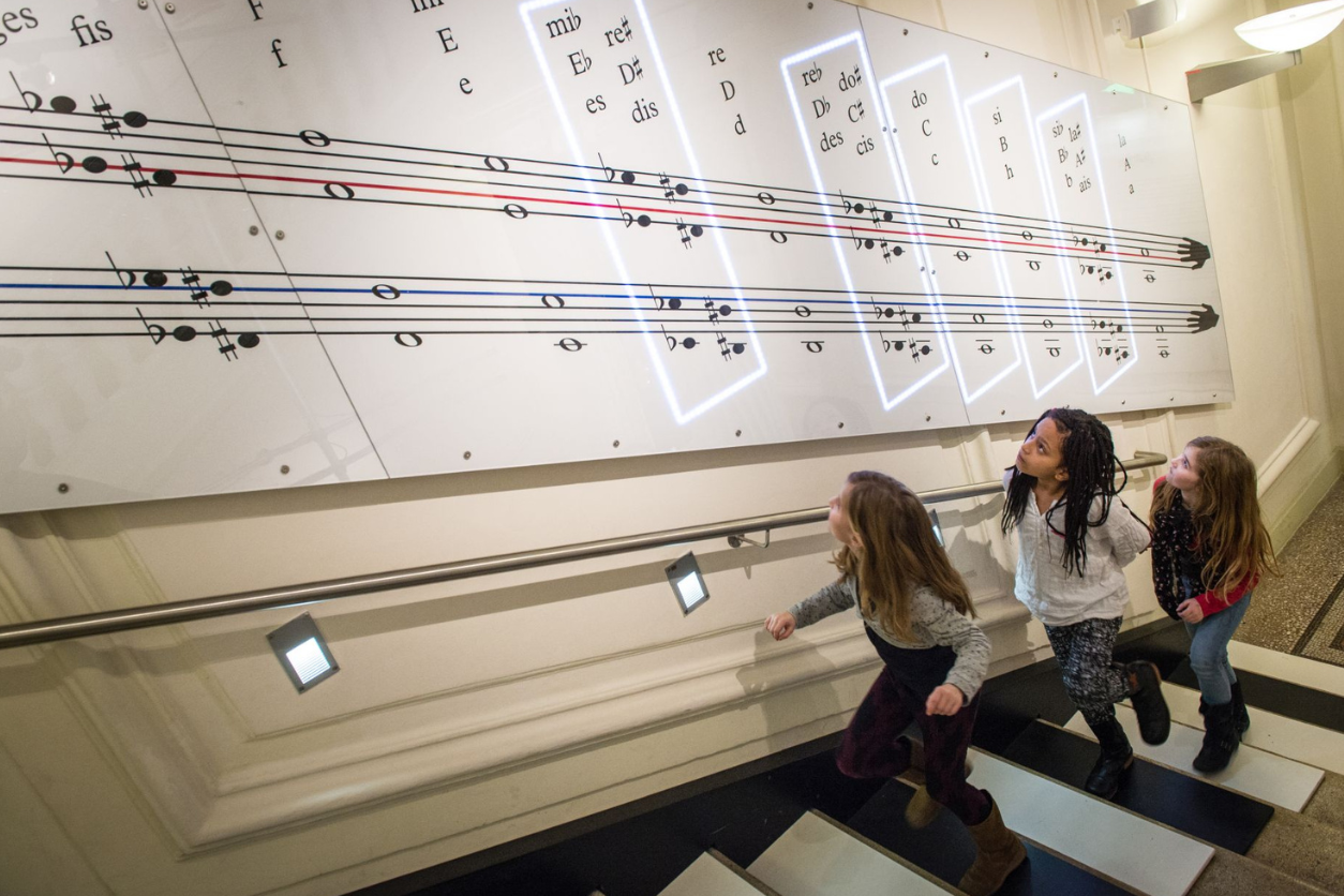 Foto: Drei Kinder gehen eine Stiege hinauf uns schauen auf Noten