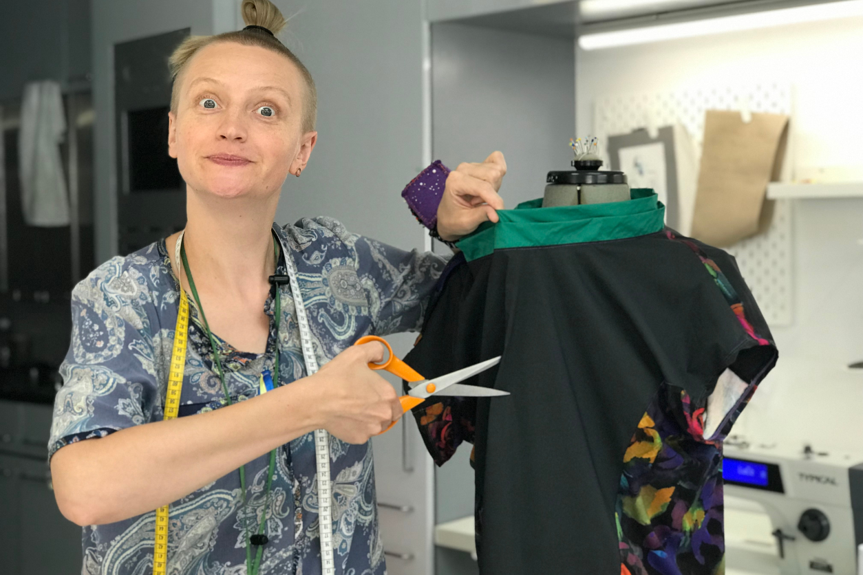 Foto: Eine Frau hält ein Kleid und eine Schere in den Händen