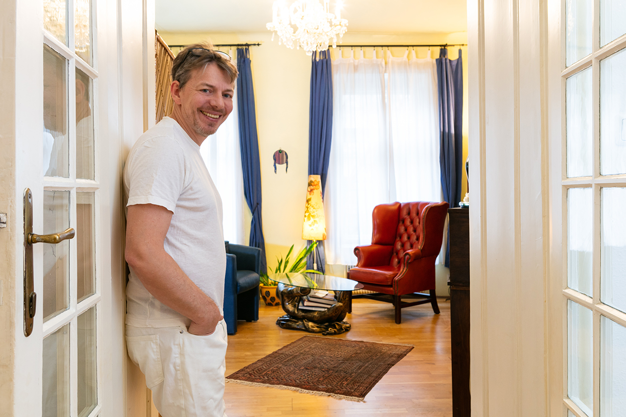 Foto: Eine Person steht in der Tür. Im Hintergrund ist ein Wartezimmer mit zwei Sesseln und einem Tisch