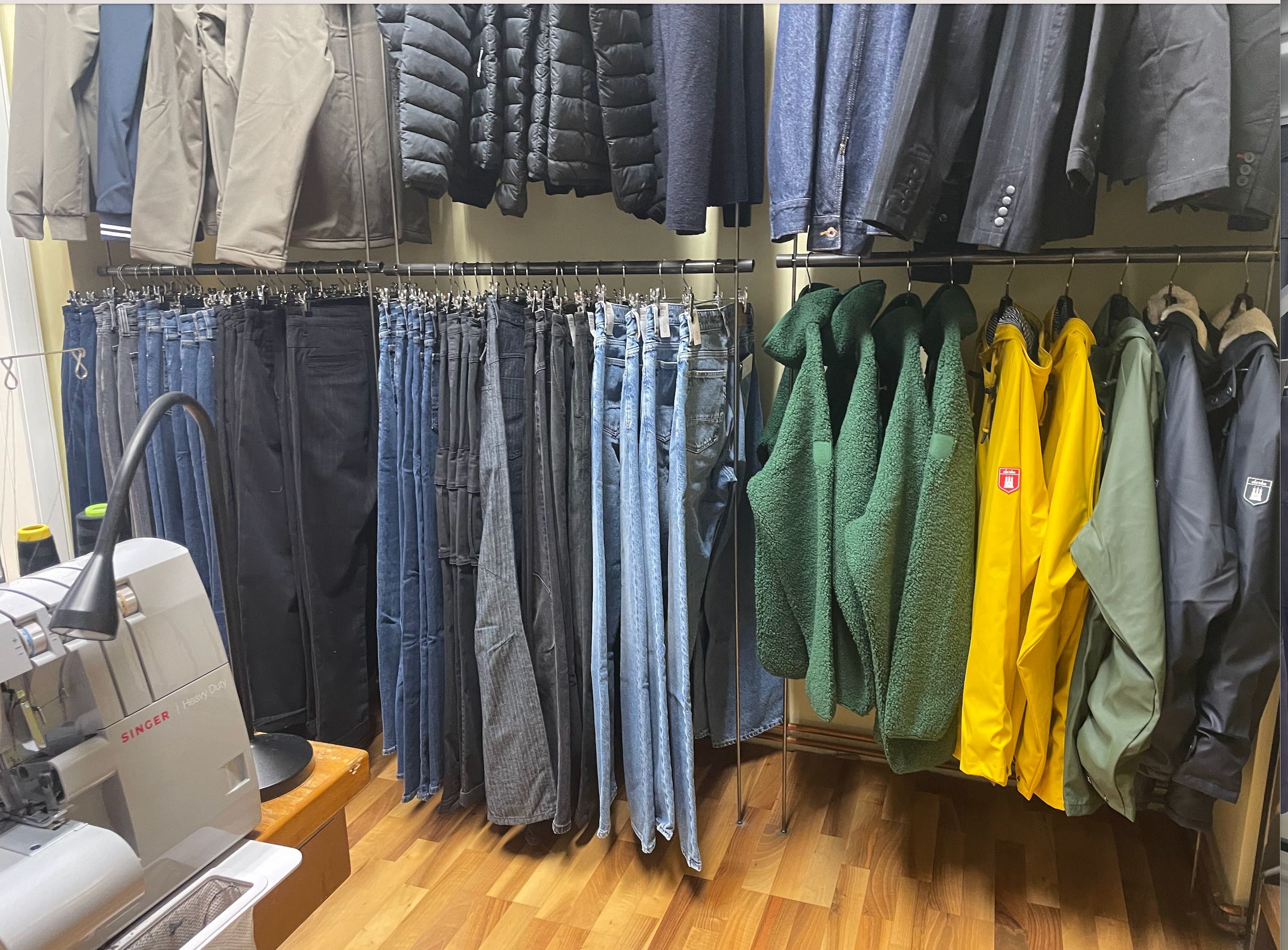 Foto: Zwei Kleiderstangen sind übereinander an einer Wand montiert. Auf den Kleiderstangen hängen verschiedene Kleidungsstücke