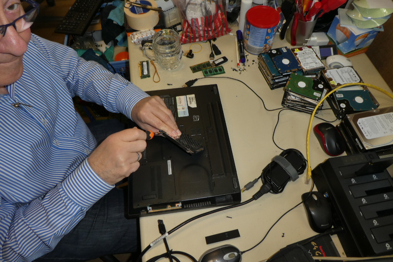 Foto: Ein Mann repariert auf einem Schreibtisch einen Laptop