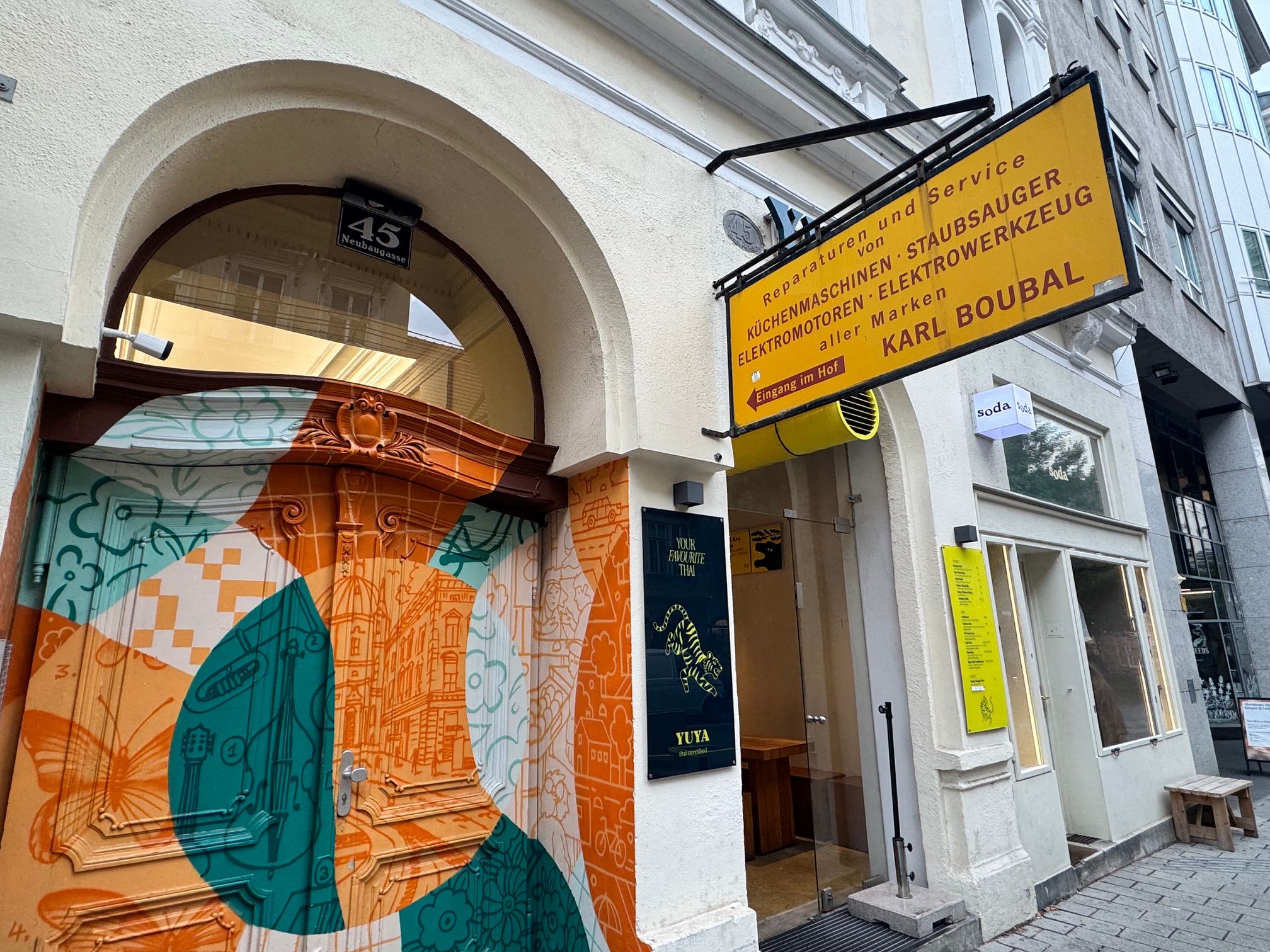 Foto: Außen Ansicht des Geschäftes mit sehr buntem Portal. Firmenschild in Gelb mit der Aufschrift von Reparaturen und Service Karl Boubal