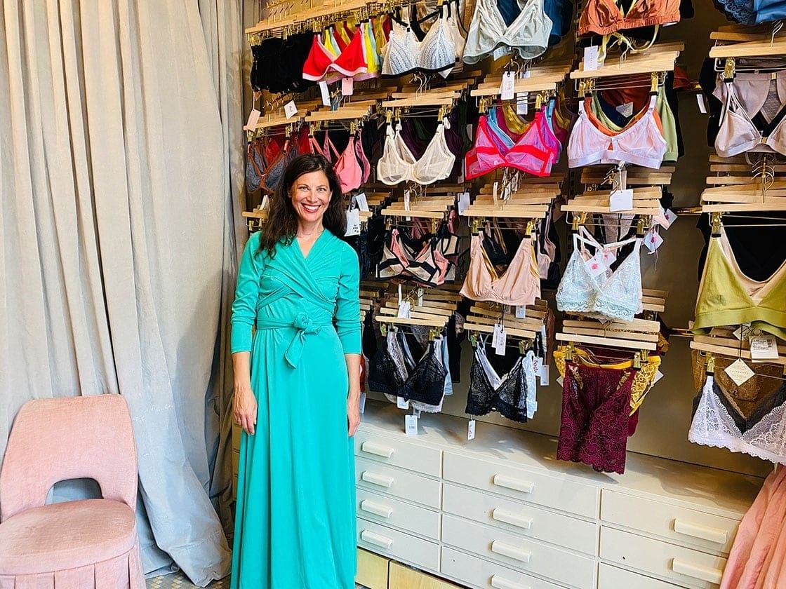 Foto: Eine Frau steht vor vier Reihen ausgestellter BHs.