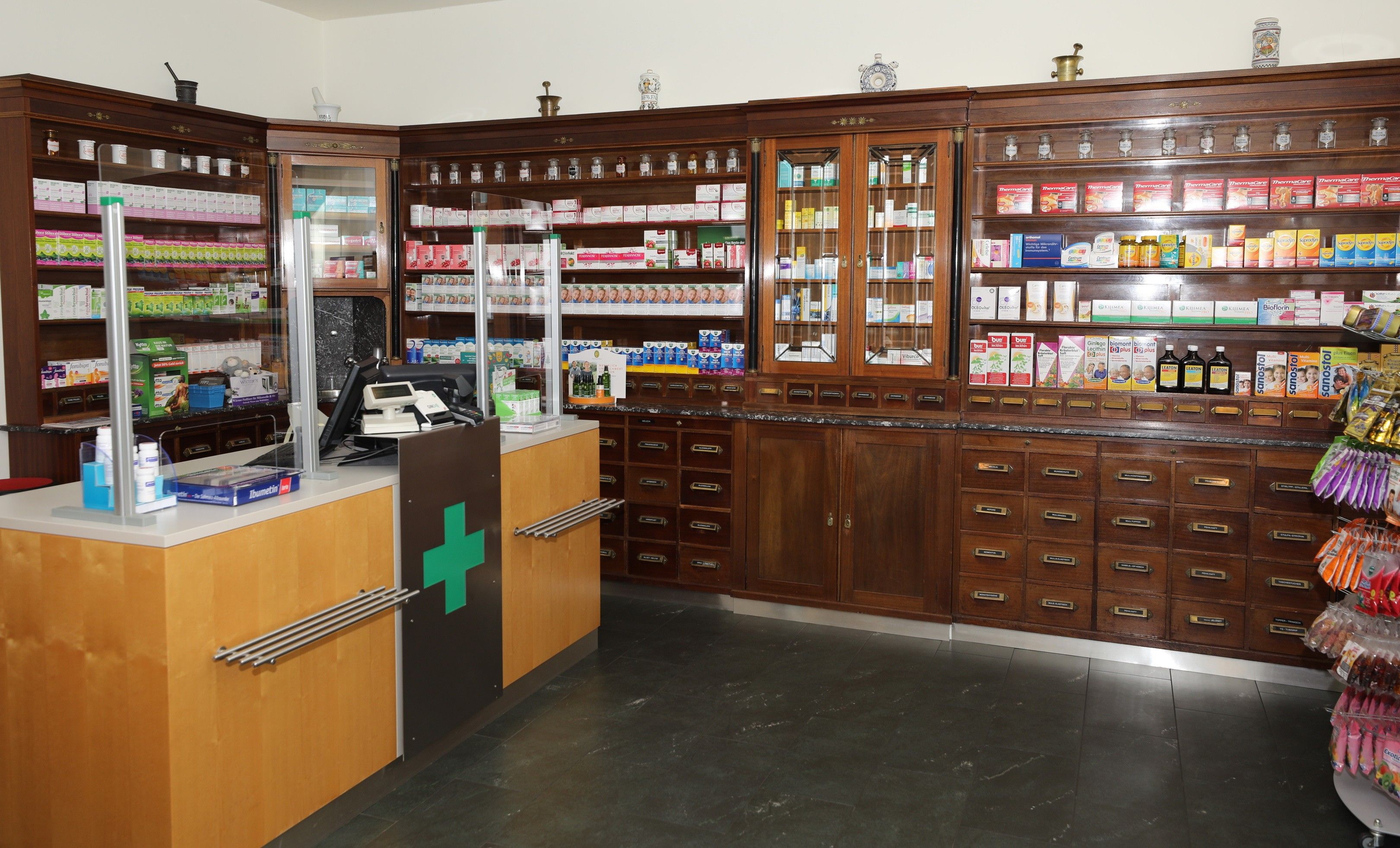 Foto: Innenbereich der Apotheke zur alten Jägerzeile mit unterschiedlichen Arzneimitteln, ausgestellt in Vintage-Holzregalen