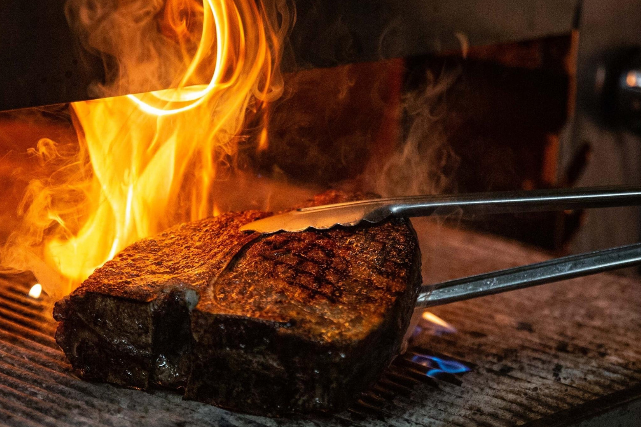 Foto: Ein Steak auf einem Grill mit Flammen