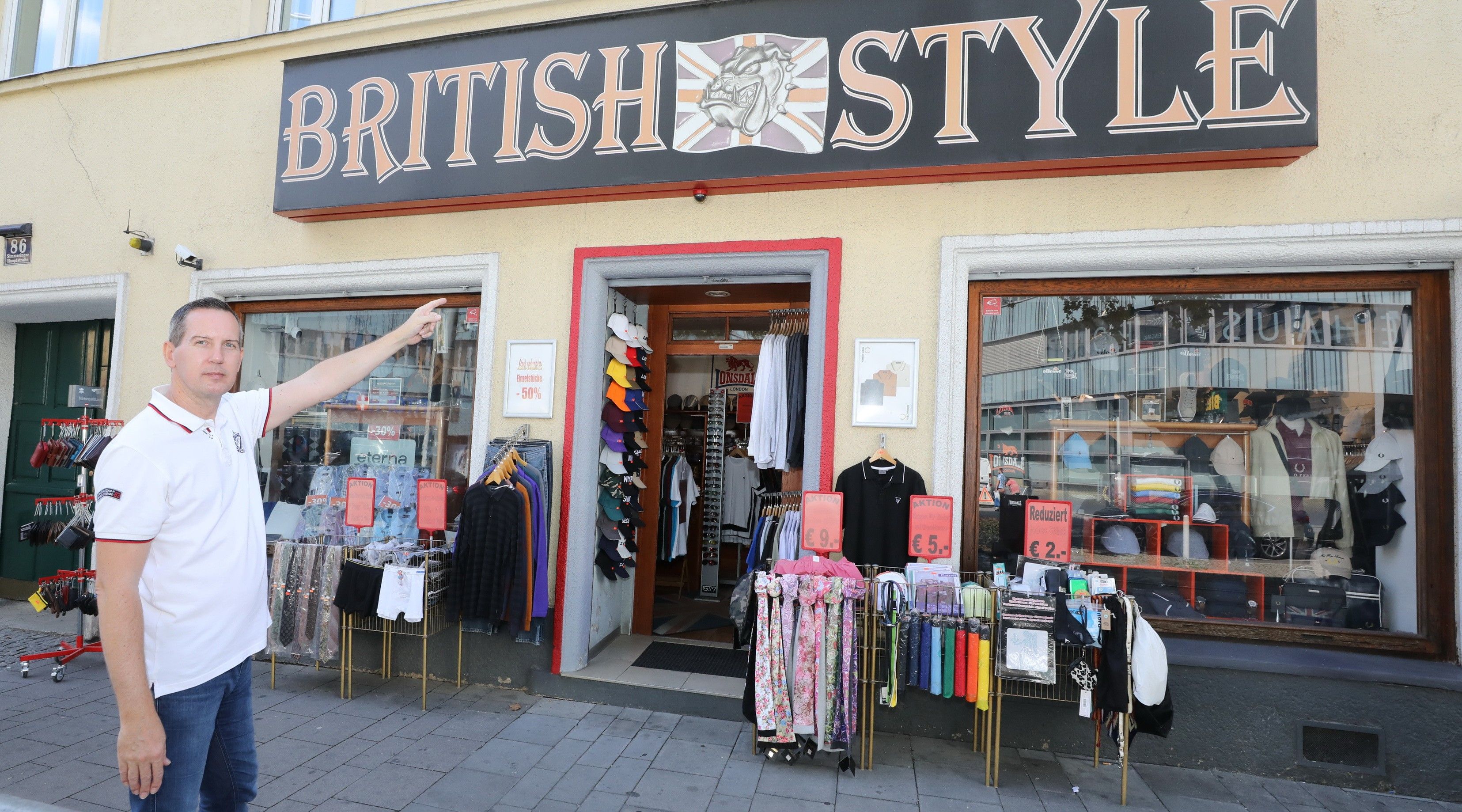 Foto: Eingangsbereich des Shops Britisch Style mti verschiedenen Kleidungsstücken wie Schals und Sonderangeboten davor.