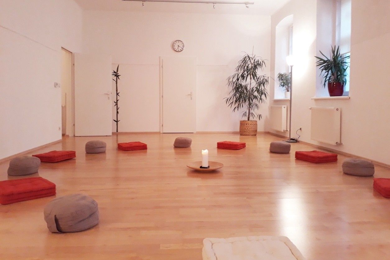 Foto: Eine Yogaraum mit einer Kerze in der Mitte und Yogasitzkissen im Kreis herum