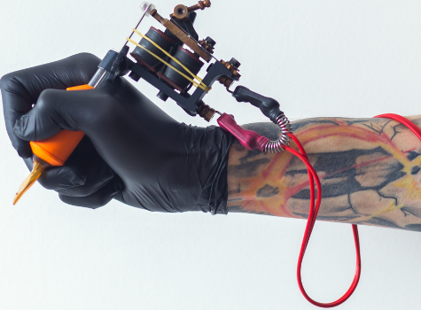 Foto: Ein Arm mit einem Tattoo Gerät in der Hand