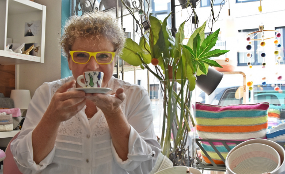 Foto: Eine Frau hält eine Kaffeetasse in die Kamera