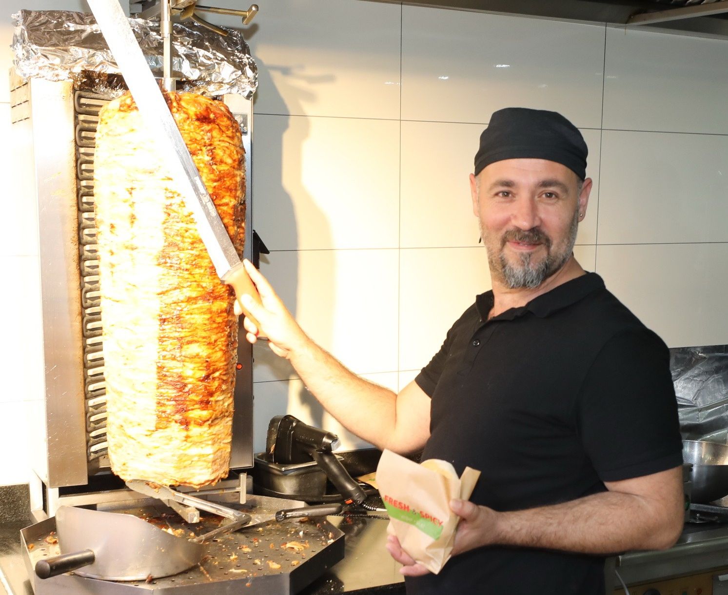 Foto: Mann vor Kebap-Spieß der gerade einen Kebap vorbereitet