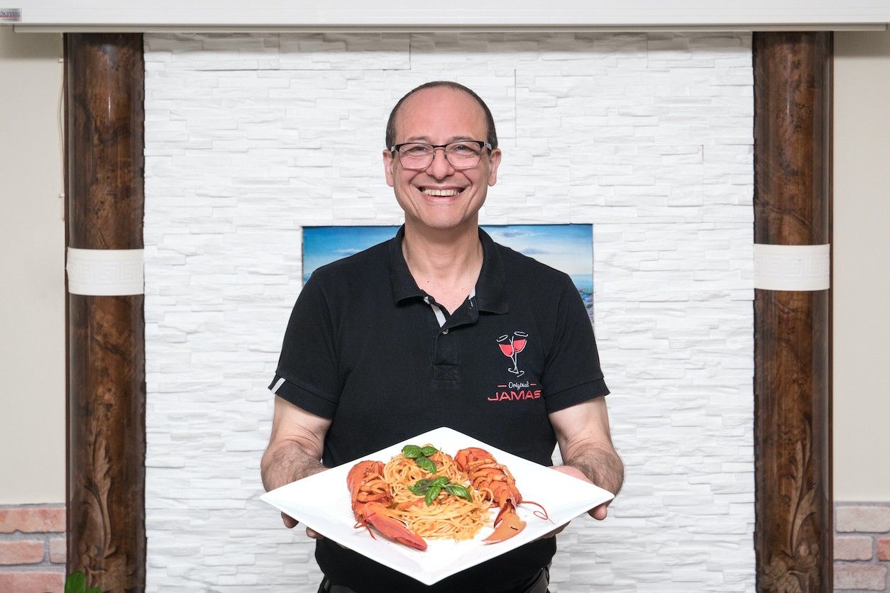 Foto: Ein Mann zeigt ein griechisches Gericht auf einem Teller