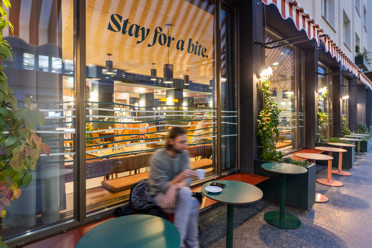 Foto: Geschäftslokal magdas aussen mit einer Person die Kaffee trinkt