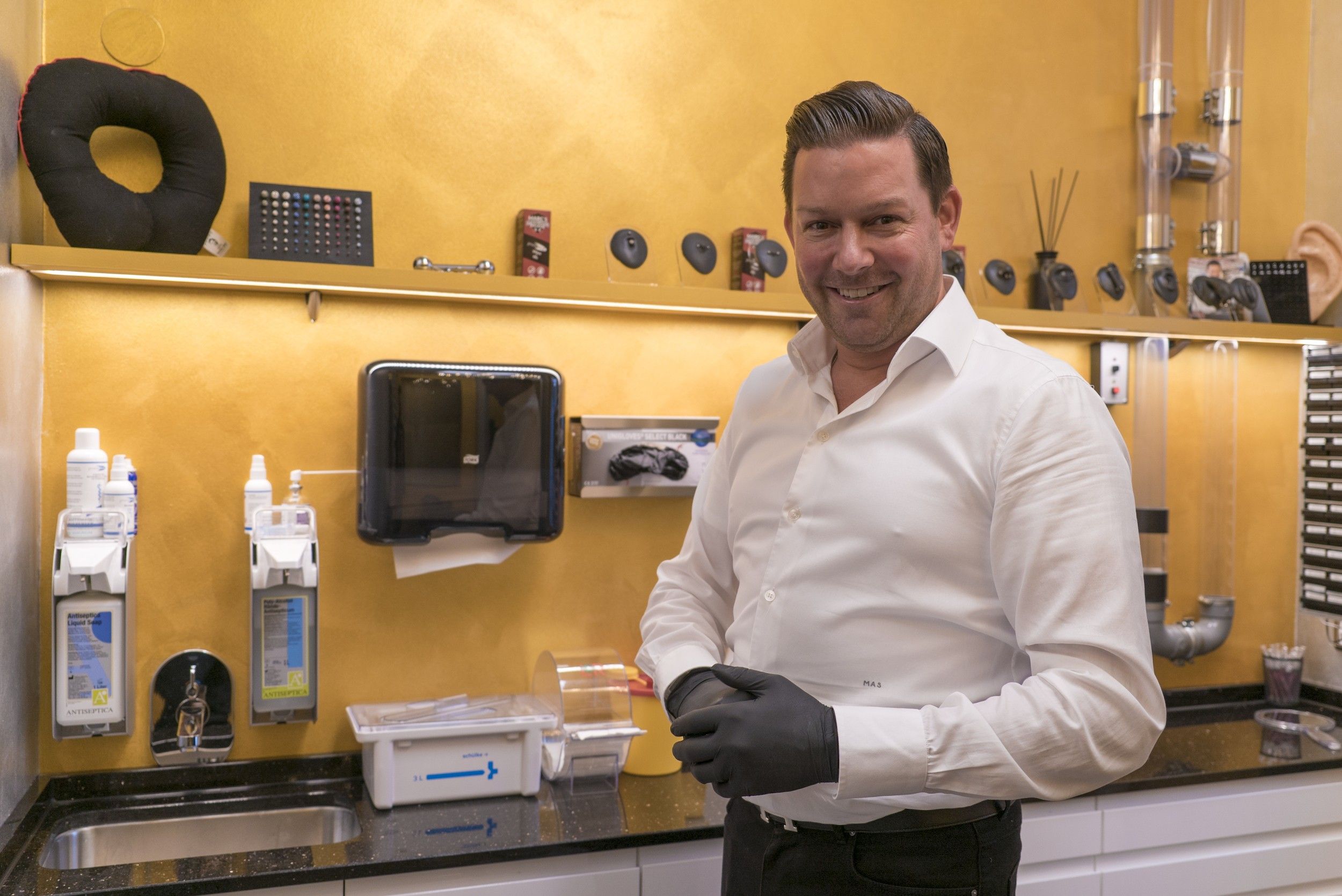 Foto: Ein Mann mit schwarzen Handschuhen im Piercing Studio