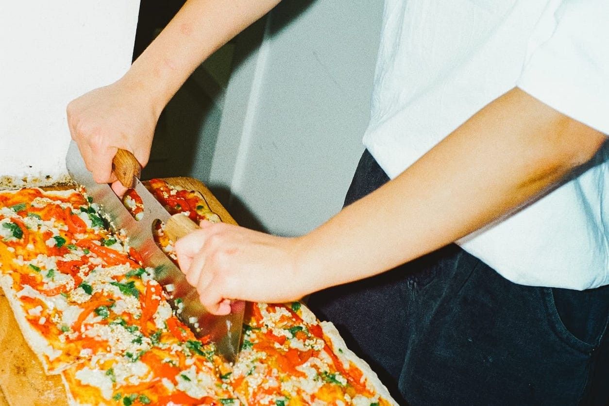 Foto: Pizza die gerade geschnitten wird