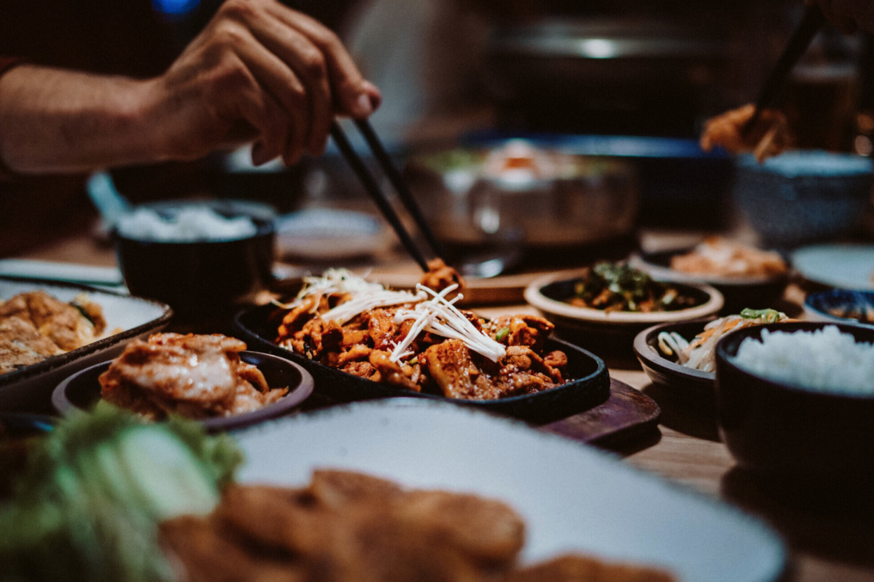 Foto: Koreanisches Essen und eine Person nimmt etwas mit Stäbchen