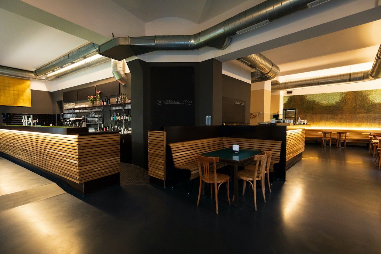 Foto: Restaurant von Innen. Eine Lanke Tecke und ein Tisch mit Stühlen.