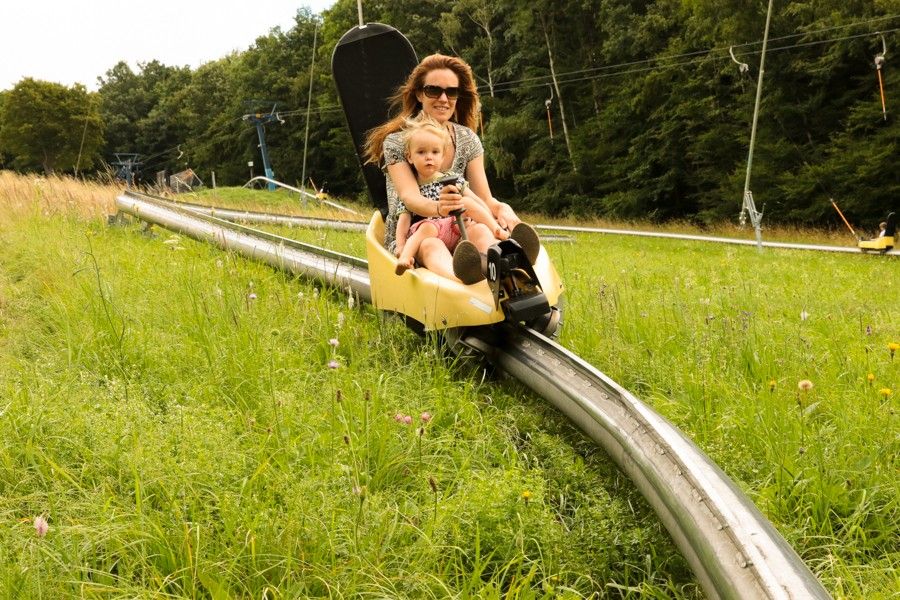 Foto: Eine Frau mit Kind sitzt in der Sommerrodelbahn auf der Hohen Wand Wiese