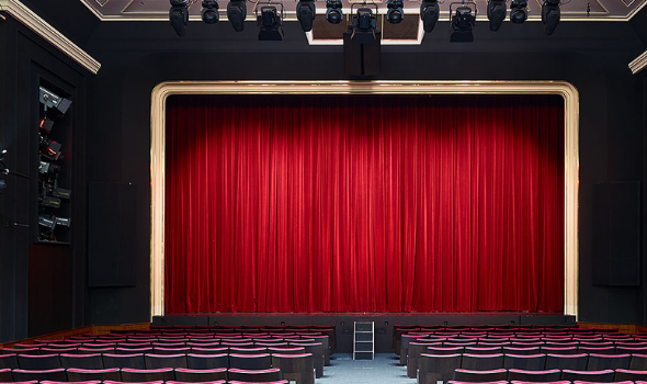 Foto: Zeigt eine Bühne mit heruntergelassenem roten Vorhang