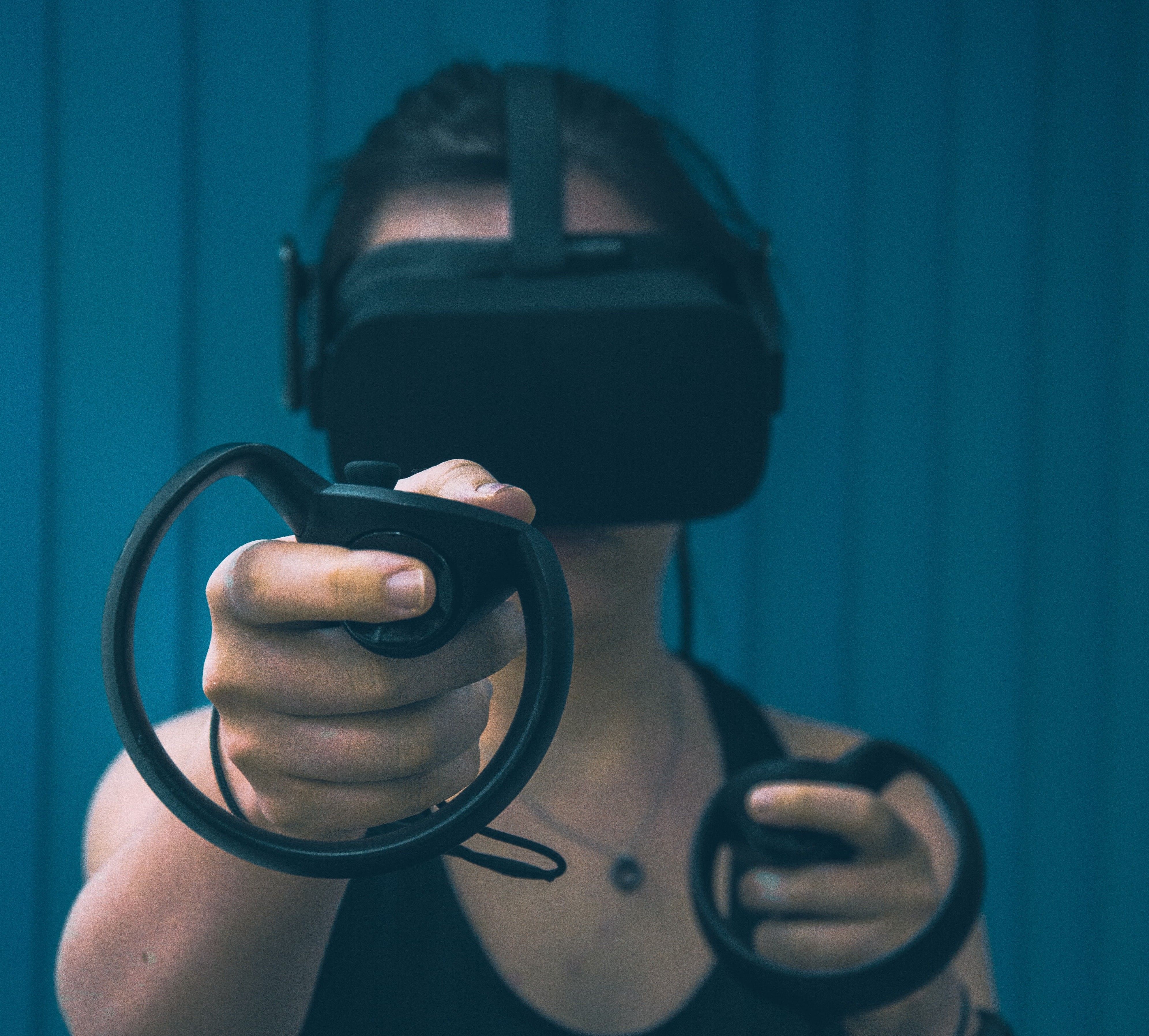 Foto: Eine Person mit einer VR Brille auf und Joysticks in der Hand